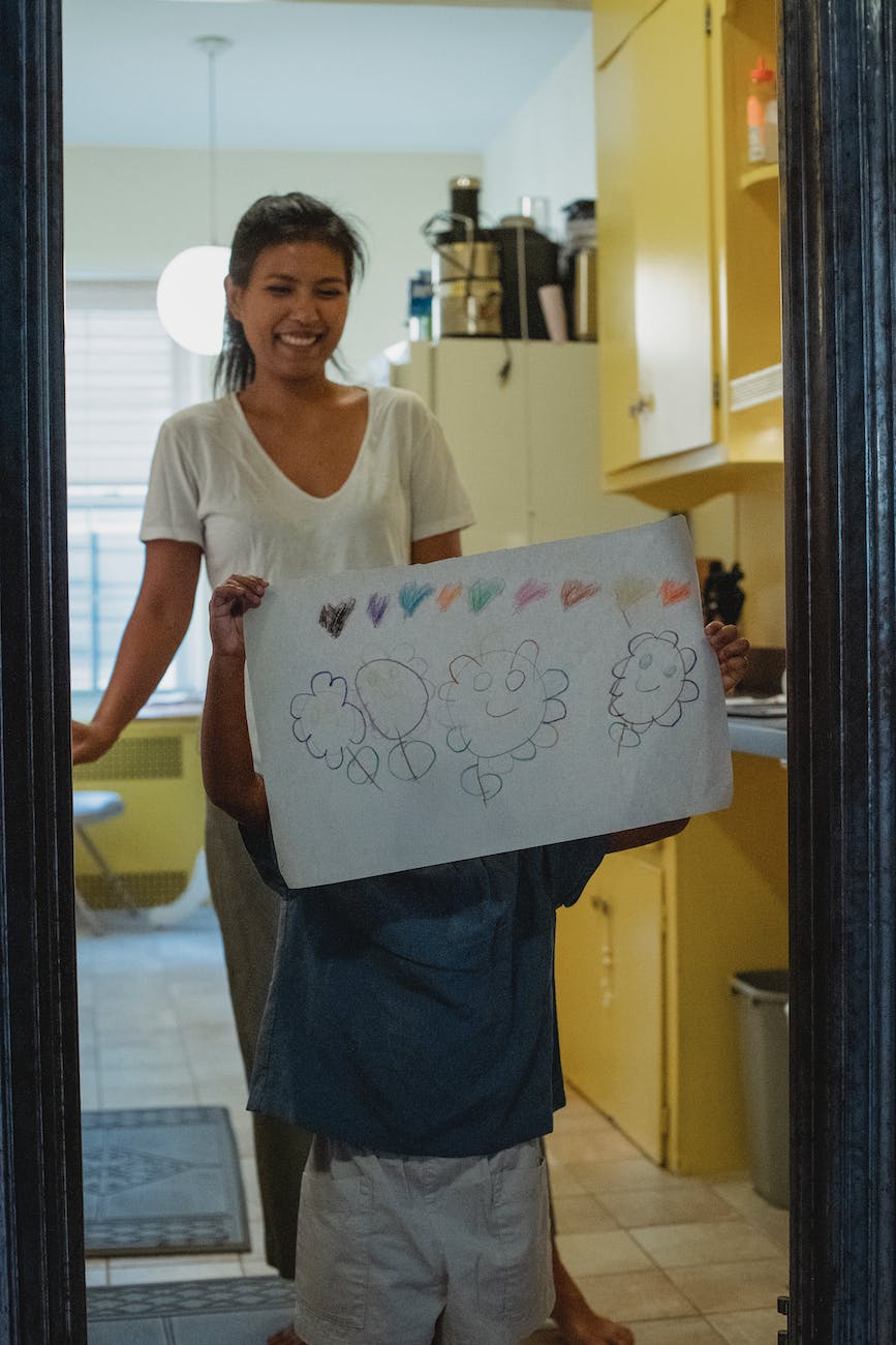 kid demonstrating drawing near happy ethnic mother at home
