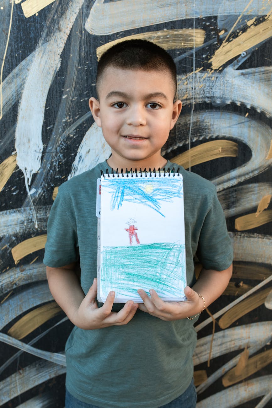 boy in gray crew neck t shirt holding his drawing