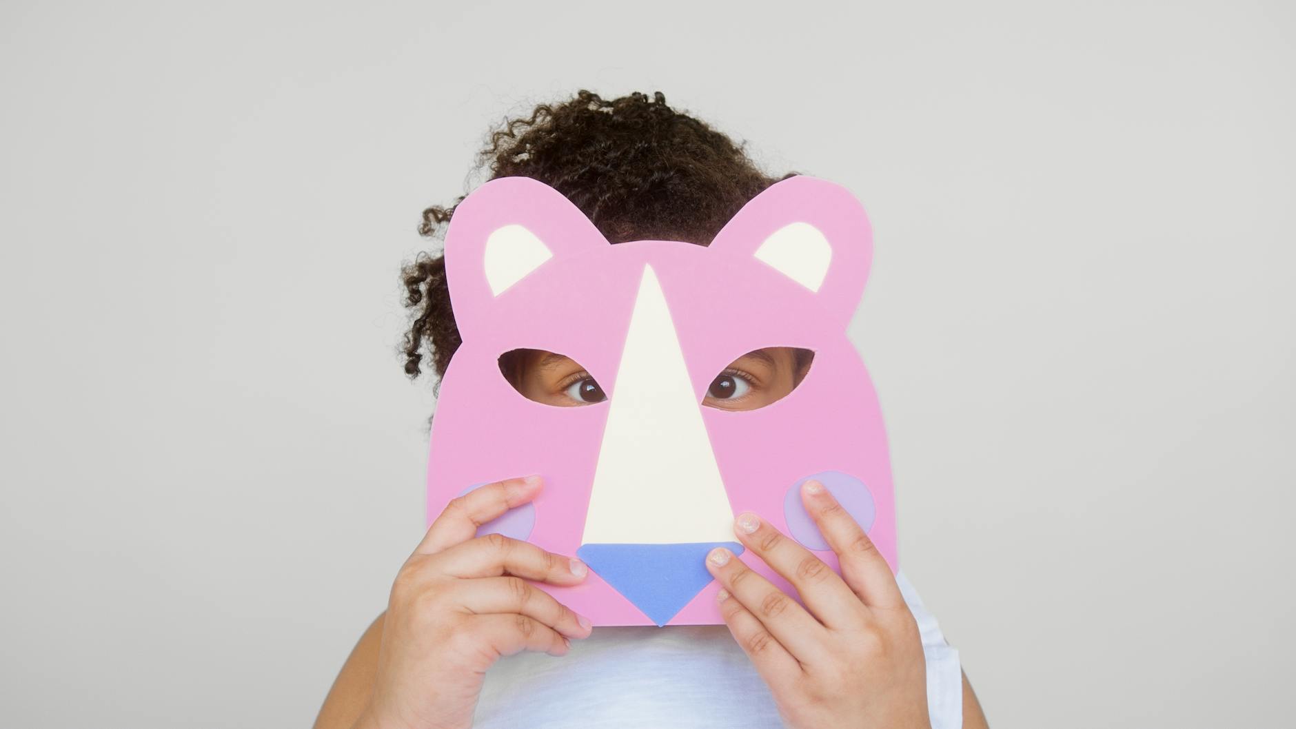 girl covering her face with a cutout animal mask