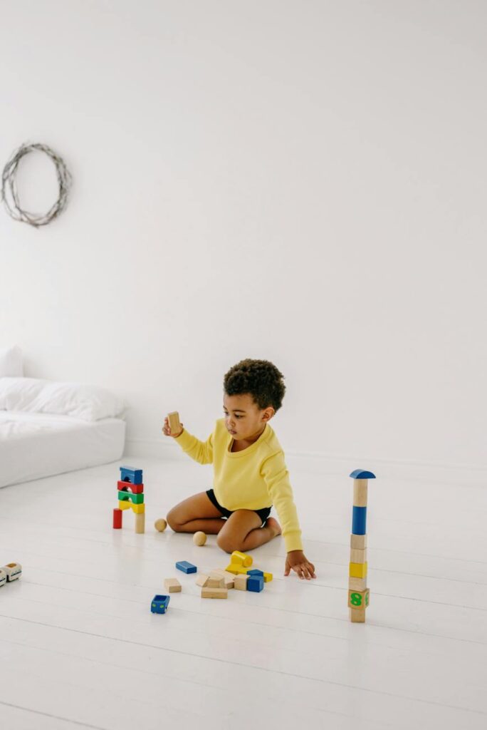 boy in yellow t shirt playing with wooden blocks